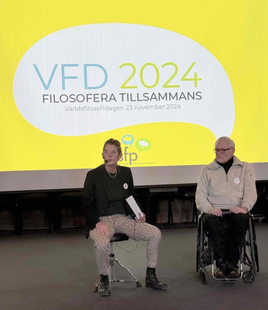 Tulsa sitter vid podiet vid en av föreningens Världsfilosofidagar